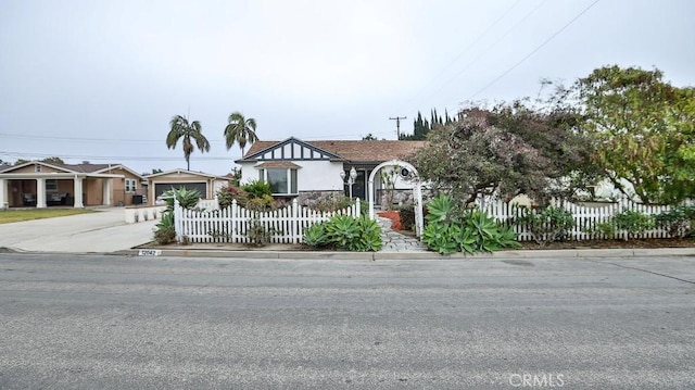 tudor home featuring a fenced front yard and concrete driveway