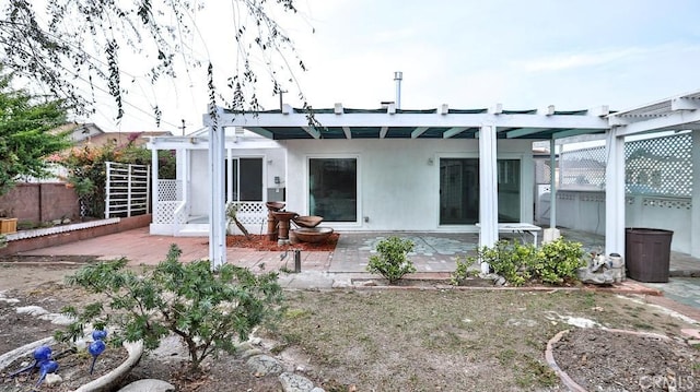 back of property featuring stucco siding, a pergola, a patio, and fence