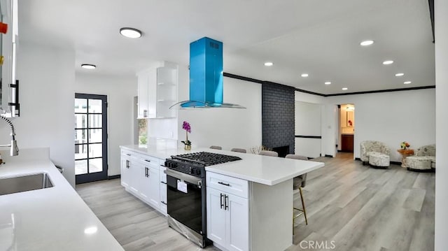 kitchen with gas stove, a breakfast bar, a sink, white cabinetry, and exhaust hood