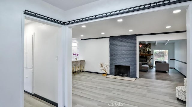 living room with recessed lighting, a brick fireplace, baseboards, and wood finished floors