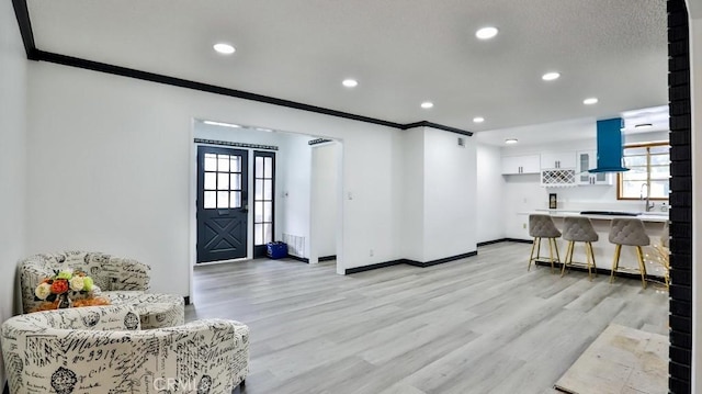 living room featuring crown molding, recessed lighting, baseboards, and light wood-type flooring