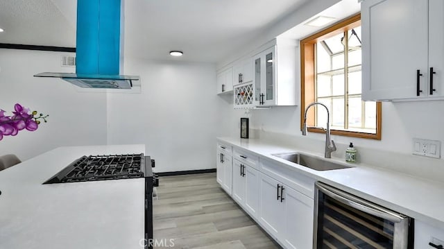 kitchen featuring ventilation hood, wine cooler, stainless steel range with gas stovetop, light countertops, and a sink