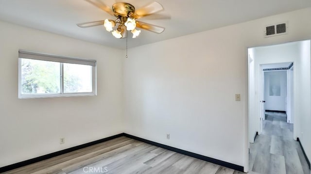 spare room featuring visible vents, light wood-style flooring, a ceiling fan, and baseboards