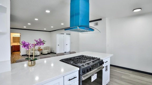 kitchen with white cabinets, light countertops, light wood-style floors, and gas range oven