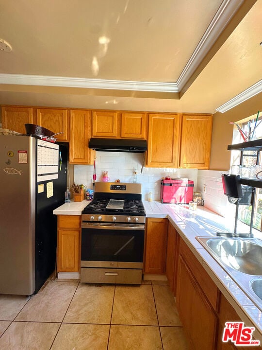 kitchen featuring appliances with stainless steel finishes, tasteful backsplash, sink, ornamental molding, and light tile patterned flooring