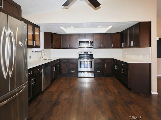 kitchen featuring appliances with stainless steel finishes, dark wood-type flooring, lofted ceiling, dark brown cabinetry, and sink