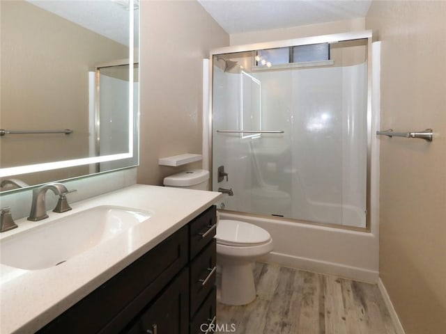 full bathroom featuring hardwood / wood-style floors, enclosed tub / shower combo, vanity, and toilet