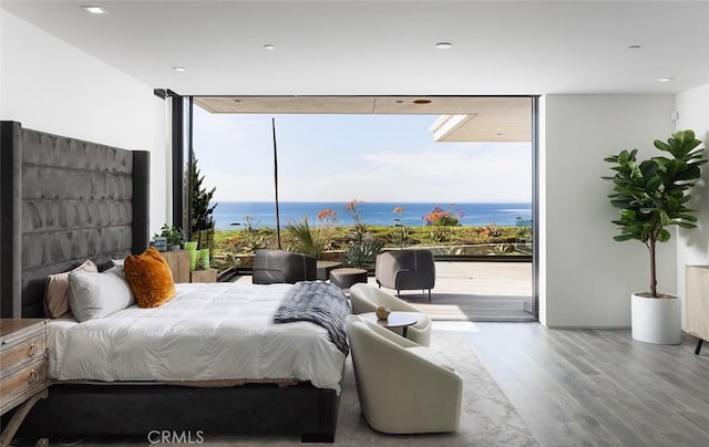 bedroom featuring hardwood / wood-style floors, a water view, and access to outside