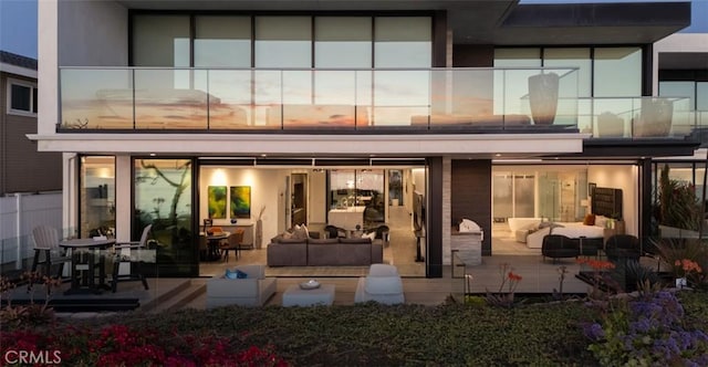 back house at dusk featuring an outdoor living space and a patio area