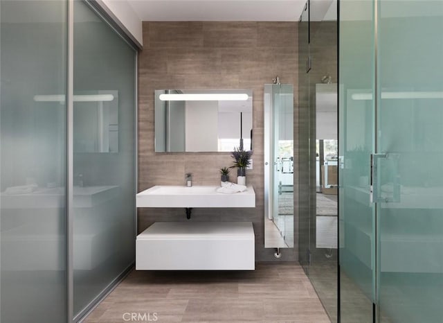 bathroom with an enclosed shower, vanity, and tile walls