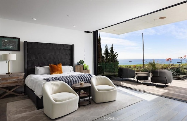 bedroom with hardwood / wood-style flooring and a water view