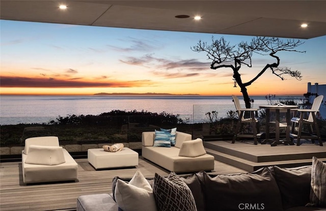 deck at dusk featuring a water view and outdoor lounge area