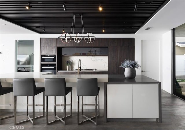 kitchen with a breakfast bar area, sink, an island with sink, and dark brown cabinets