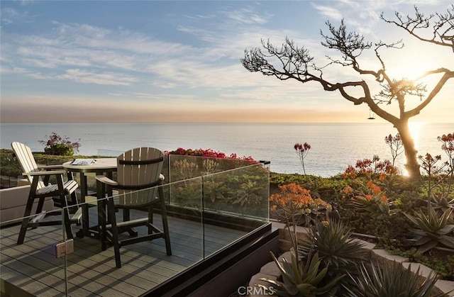 balcony at dusk featuring a water view