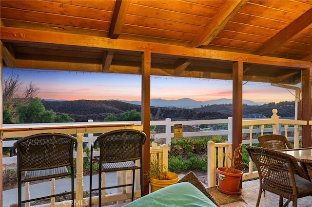 sunroom / solarium with wood ceiling, beam ceiling, a mountain view, and a healthy amount of sunlight