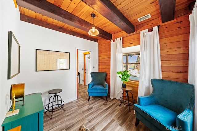 living area with beam ceiling, hardwood / wood-style flooring, wood walls, and wood ceiling