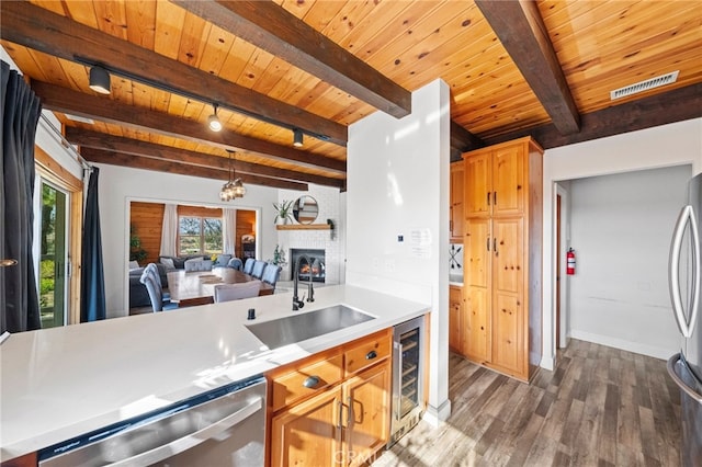 kitchen with appliances with stainless steel finishes, wood ceiling, wine cooler, sink, and beam ceiling