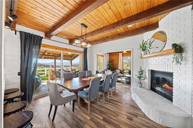 dining room featuring wood ceiling, a healthy amount of sunlight, beamed ceiling, and a fireplace