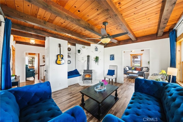 living room featuring wooden ceiling, a wood stove, and beamed ceiling