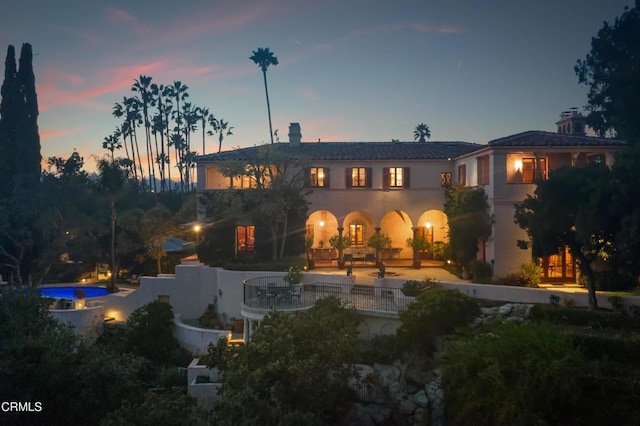 back house at dusk with a patio area