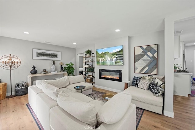 living room with light hardwood / wood-style flooring and a notable chandelier