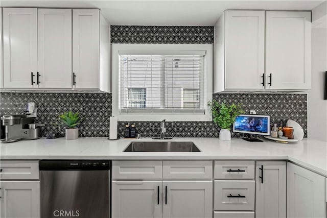 kitchen with stainless steel dishwasher, white cabinets, backsplash, and sink