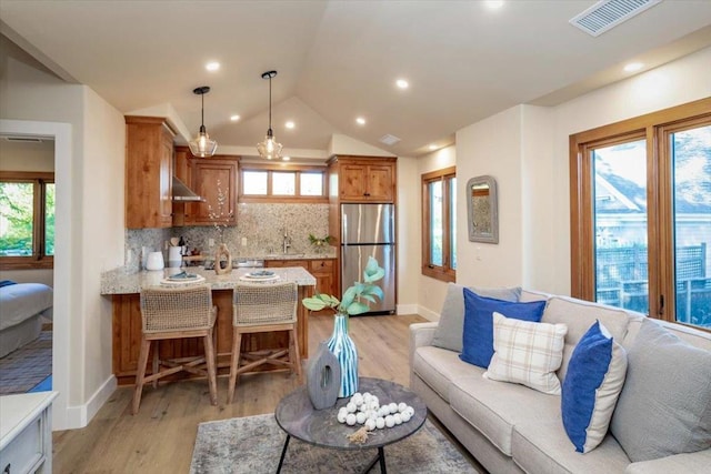 living room with lofted ceiling, light hardwood / wood-style floors, and sink