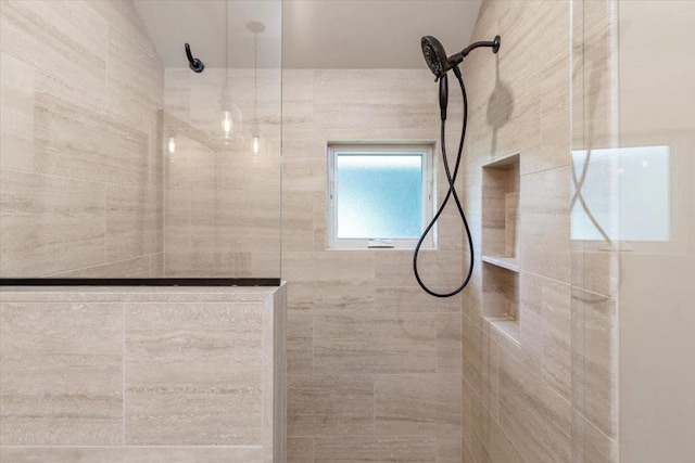 bathroom featuring tiled shower and lofted ceiling