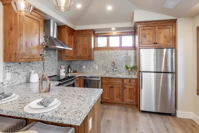 kitchen with a breakfast bar area, stainless steel appliances, vaulted ceiling, wall chimney exhaust hood, and sink