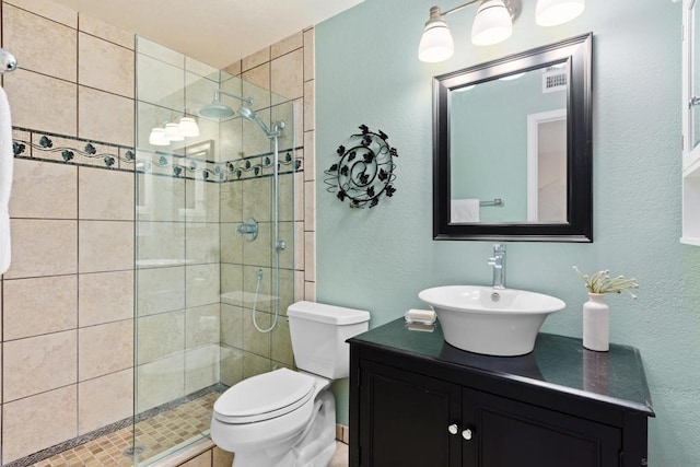 bathroom featuring toilet, vanity, and a tile shower