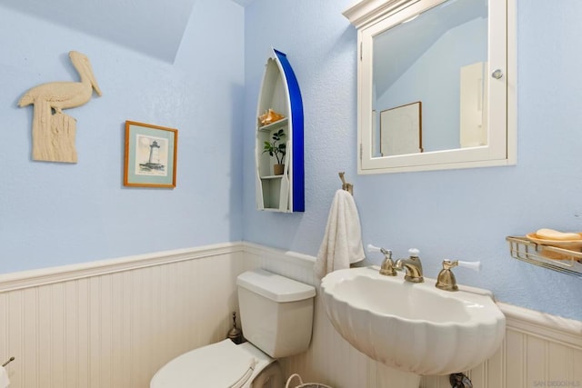 bathroom featuring toilet, sink, and lofted ceiling