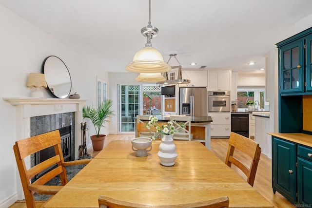 dining space featuring light wood-type flooring, a tiled fireplace, and sink