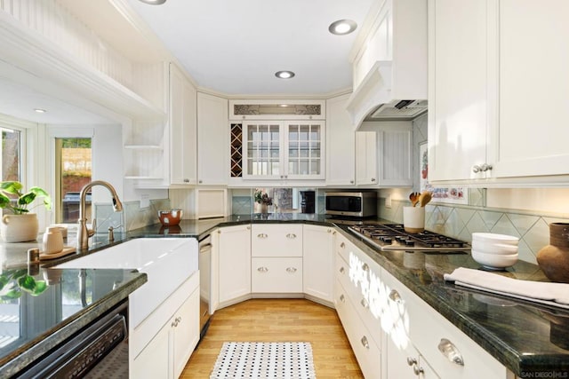 kitchen with custom exhaust hood, sink, white cabinetry, light wood-type flooring, and appliances with stainless steel finishes