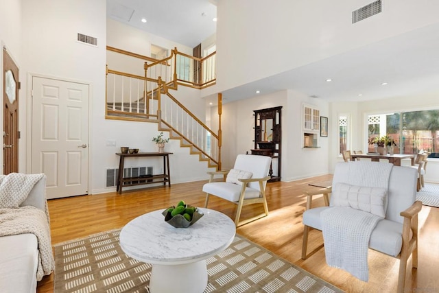 living room featuring light wood-type flooring and a high ceiling