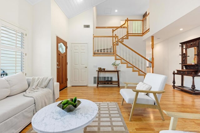 living room with light hardwood / wood-style flooring, crown molding, and a towering ceiling