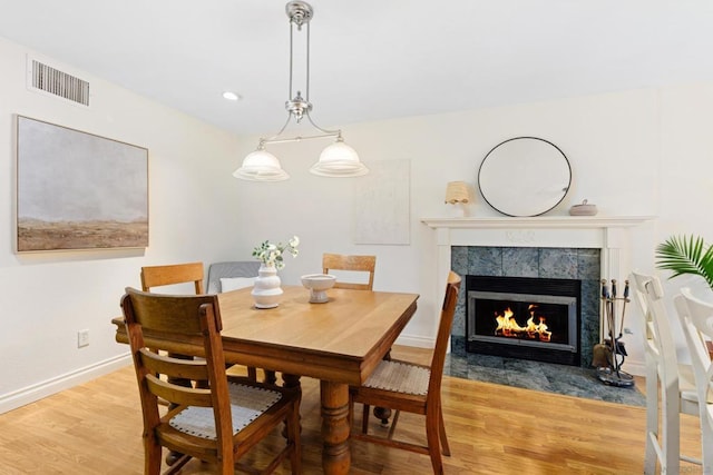 dining space with light wood-type flooring and a fireplace