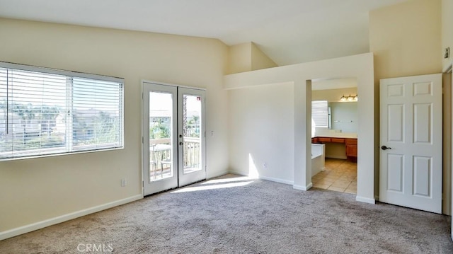 spare room with light carpet, vaulted ceiling, and french doors