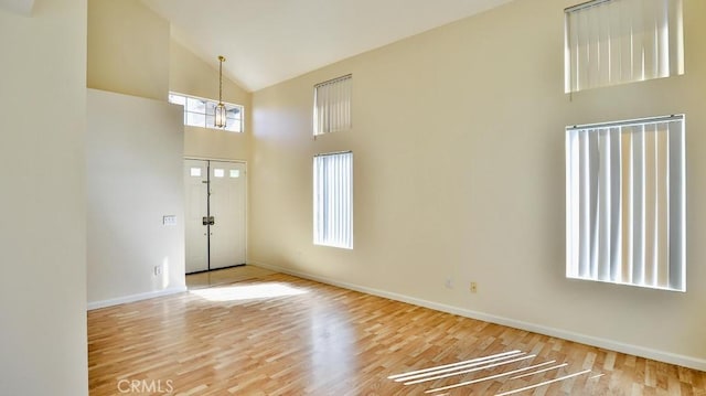 foyer entrance featuring a notable chandelier, plenty of natural light, high vaulted ceiling, and light hardwood / wood-style flooring