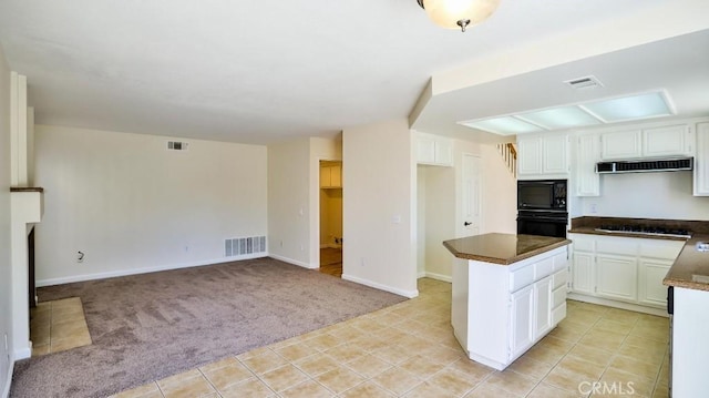 kitchen featuring white cabinetry, range hood, a kitchen island, black appliances, and light carpet