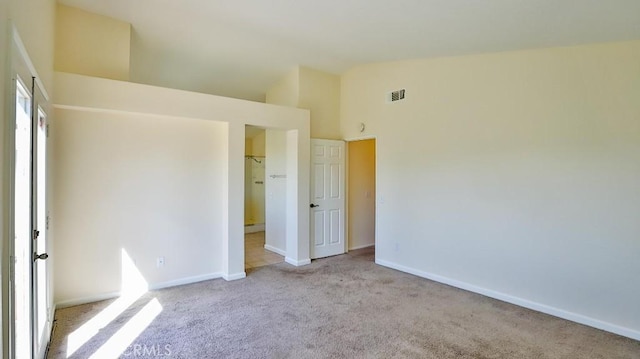 unfurnished bedroom featuring light carpet and high vaulted ceiling