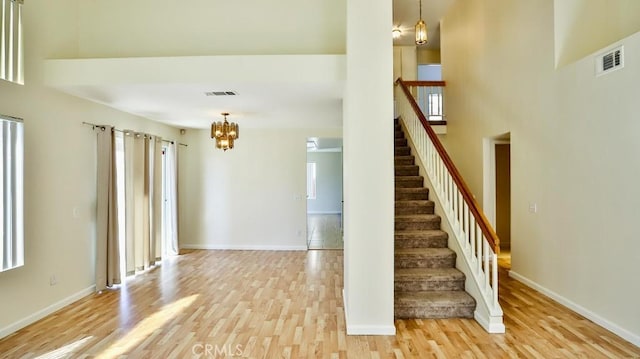 stairs featuring hardwood / wood-style floors, plenty of natural light, a notable chandelier, and a high ceiling