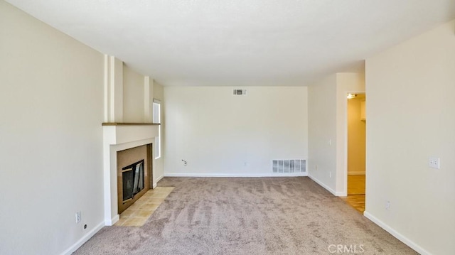 unfurnished living room with light carpet and a tiled fireplace