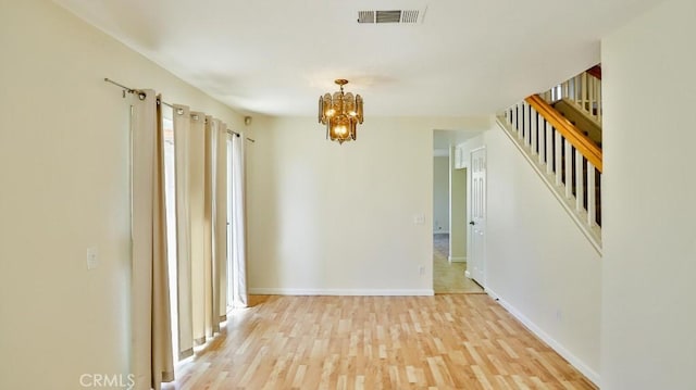 unfurnished room with light wood-type flooring and an inviting chandelier