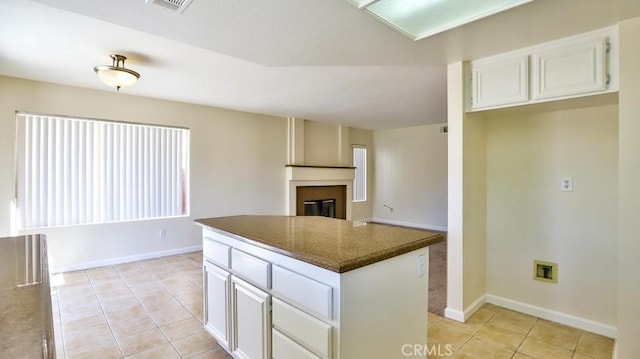 kitchen featuring white cabinetry, dark stone countertops, a kitchen island, and light tile patterned floors