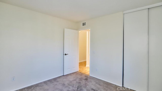 unfurnished bedroom with a closet and light colored carpet