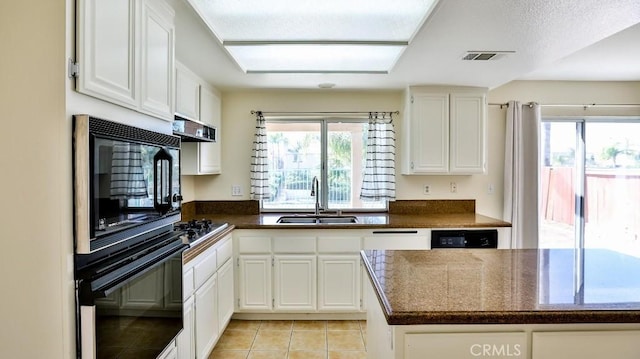 kitchen featuring sink, light tile patterned flooring, range hood, black appliances, and white cabinets