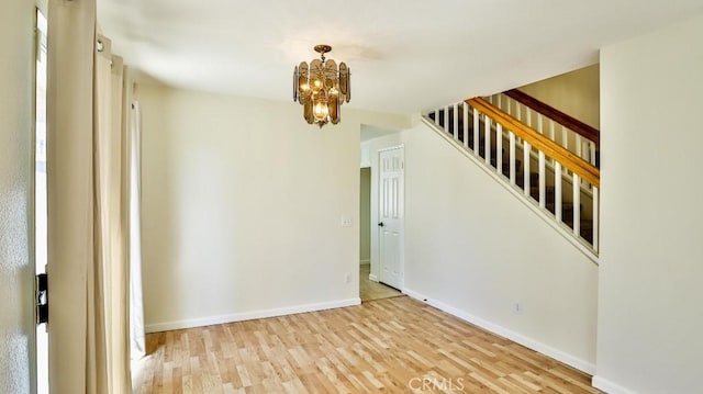 empty room with light hardwood / wood-style flooring and a chandelier