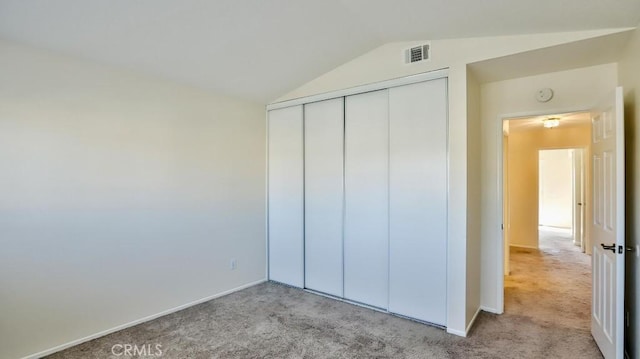 unfurnished bedroom with light carpet, lofted ceiling, and a closet