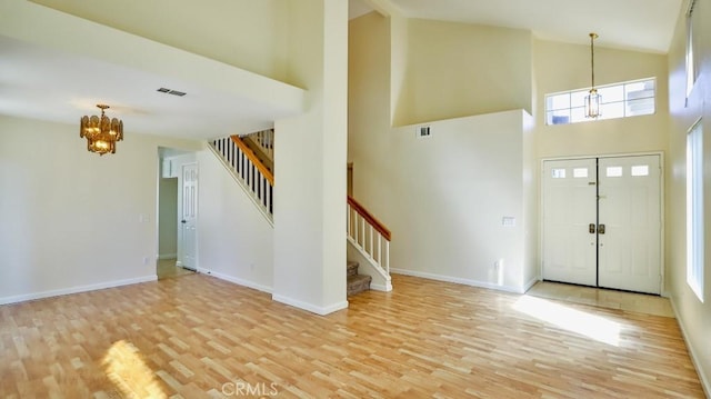 foyer featuring a wealth of natural light, light hardwood / wood-style floors, high vaulted ceiling, and a notable chandelier