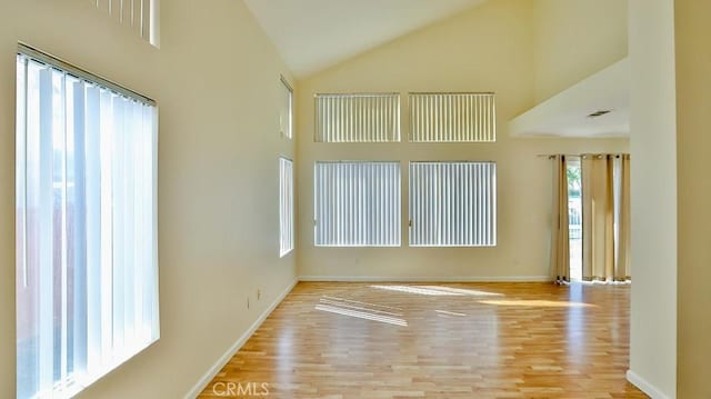 spare room with light hardwood / wood-style floors and high vaulted ceiling